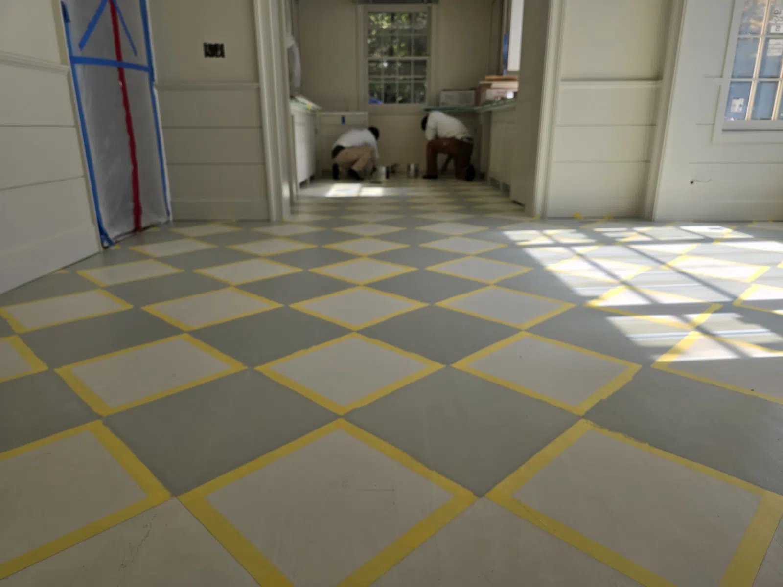 Checkered floor taped off for painting with workers in background — Alvarez' Painting in Charlottesville